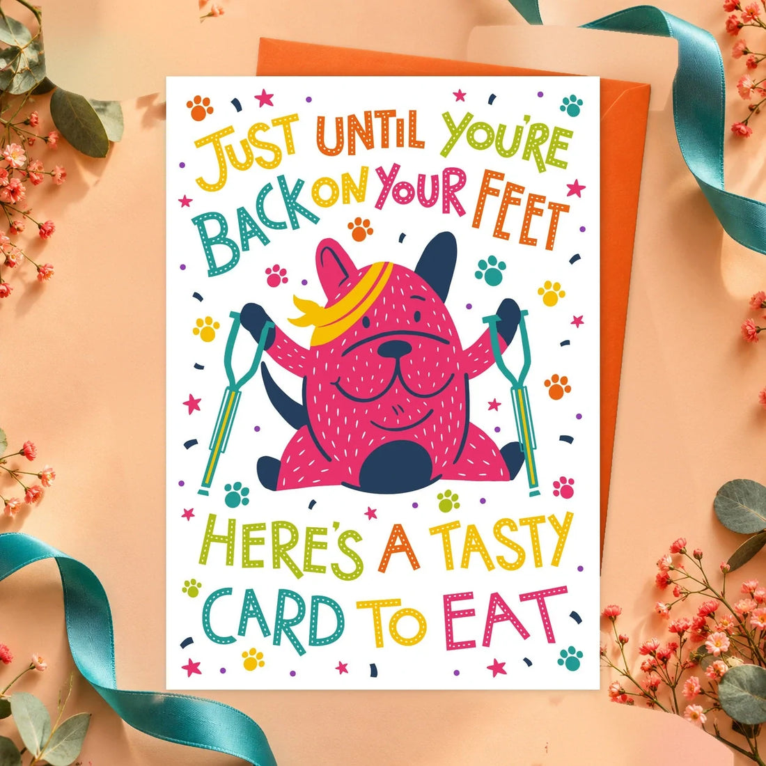 Back on Your Feet – Edible Dog Get Well Soon Card, bacon flavour by Scoff Paper, shown with an orange envelope